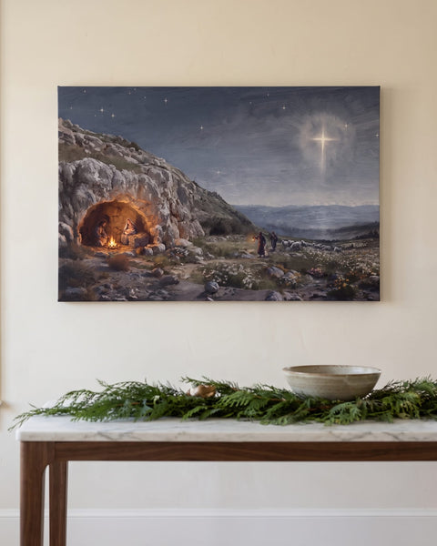 Nativity night canvas of the Holy Family in a firelit cave under a cross-shaped star, front view on an ivory plaster wall