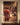 Realist canvas of Christ seen from behind walking toward the cross, hung straight-on above a walnut console