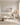 Neutral shoreline canvas above a bouclé sofa in a quiet luxury living room