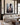 Christian canvas of Christ reaching down in the mud hanging above a cream linen sectional in a panelled living room with brass sconces
