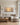 Extra-wide sunset Galilee canvas centered above a cream linen sectional in a coastal luxury living room
