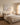 Soft coastal wall art centered above a linen headboard in a warm neutral bedroom