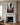 Jesus reaching a scarred hand out of the mire, canvas print resting above a carved white marble fireplace with brass candlesticks