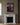 Hung over a white Carrara marble fireplace with brass candlesticks and two stacked books on the mantel, deep greige panelled walls