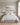 Pastel meadow and lake canvas above an upholstered linen headboard in a bright daylit primary bedroom