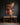 Canvas of Jesus before the cross above a wooden kneeling bench and candle in a home prayer room