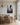 Christian wall art of Christ's outstretched nail-scarred hand hanging in a coastal dining room with a linen-draped oak table and brass chandelier