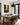 Forest path canvas on a white wall beside a rustic oak dining table with black chairs