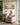 Woman in her sixties holding a coffee mug in a sunroom armchair beneath the panoramic Galilee canvas
