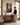 Woman pausing with one hand on a walnut console in a sunlit Craftsman sitting room, looking up at the canvas of the healing touch
