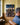 Seen from behind, a man pauses in an oak-panelled study while the canvas hangs in focus on the wall ahead of him
