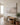 Coastal canvas above a slim oak bench with a linen throw and olive tree in a hallway