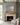 Painting-style canvas of ocean waves at dawn with the words Be Still and know that I am God over a limestone fireplace with an oak mantel