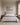 Be Still painting-style canvas of a sunrise seashore centered above an upholstered headboard in a daylight bedroom