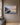 Painting-style canvas of an empty wooden rowboat on a still misty bay with 1 Peter 5:7, front view on a taupe plaster wall