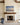 Beach sunrise painting-style canvas with the Footprints poem above a limestone fireplace and walnut mantel