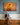 Woman with short silver hair unwinding her scarf on a hall bench, looking up at a large canvas of Jesus blessing a sheep