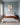 Luke 15 inspired canvas of Jesus carrying the lost lamb above a linen headboard in a blue-grey primary bedroom