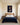 Lion guarding a sleeping lamb canvas above a camel wool headboard in a sunlit primary bedroom