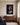Dark blue canvas of a watchful lion and a sleeping lamb above a walnut credenza in a quiet sitting room