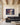 Largest size of the storm canvas on a wide cream wall above a charcoal sofa in a great room with timber trusses