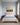 Painted-style dawn meadow canvas with Scripture lettering hanging over an upholstered headboard in a pale blue bedroom