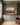 Painting-style sunrise canvas displayed between olive grey built-in bookshelves in a remodeled family room