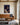Jesus crowned with thorns canvas print hanging above a tan leather sofa in a bright living room with oak beams