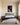 Portrait canvas of Jesus looking down at His chained wrist above a grey wool headboard in a primary bedroom