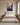Canvas of Jesus leaning over a cliff of blossoms to reach a woman, hung above an upholstered bed in a daylit bedroom