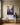 Woman in a navy sweatshirt sitting on a window bench with a notecard beside a canvas of Jesus reaching for a falling woman