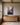 Largest 32 x 48 inch canvas of Jesus reaching from a flowering cliff, above an oak sideboard in a beamed great room