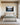 Still lake at first light canvas above an upholstered oatmeal headboard in a daylit primary bedroom