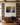 Canvas of Jesus kneeling beneath a golden tree hung between built-in bookcases above a walnut credenza in a study