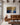 The largest 48 by 32 inch canvas above a cognac leather sofa on a wide stone-grey wall with dark walnut beams