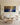 The 48 by 24 inch panoramic Gethsemane canvas above a white linen sofa in a cream panelled living room with brass sconces