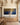 Panoramic prayer canvas above an oak sideboard in a beamed dining room with a brass chandelier