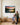 Husband and wife looking up at the sunset scripture canvas above a built-in oak bench in their family room