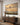 Second Coming canvas above an entryway console table with golden hallway light