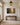 Small painting-style forest path scripture canvas above a walnut console table in a bright entry hall