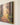 Close-up of the gallery-wrapped edge of a painting-style canvas showing sunbeams, tall trees and ferns along a forest path