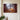 Nativity canvas with the shadow of a cross on a stone stable wall, hung on an ivory plaster wall beside a console dressed with fresh cedar