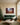 Manger and cross Christmas canvas above a forest-green velvet sofa in a cream panelled living room with a Christmas tree