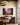 Landscape manger canvas in a dining room above a walnut sideboard with pomegranates and magnolia leaves under an iron chandelier