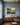 The Lord is my shepherd painted landscape canvas on a dusty blue dining room wall above a walnut sideboard with a bowl of green apples