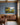 Still waters and golden trees painting-style canvas with Psalm 23 verse on a slate blue home office wall above a walnut credenza