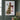 Front view of the Christmas tree and wooden cross canvas hanging on a deep green panelled wall above a console with cedar garland and brass candlesticks