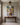 Vertical lamb and Jesus stream painting above a walnut console table in an entry hall with a brass lantern
