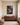 Canvas of Jesus reaching down to a worn-out lamb above a walnut credenza in a quiet prayer corner with a kneeling bench